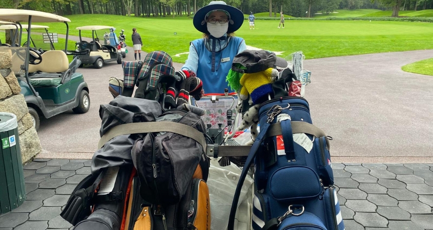 What Playing Golf in Japan Feels Like - Caddies and Shared Carts Japanese golf caddie preparing a shared cart with clubs and bags