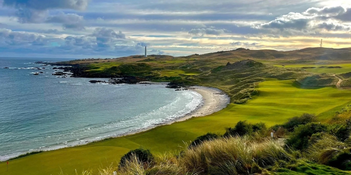 Illustrative coastal links golf scene with a white lighthouse, ocean surf, rocky headland and a green fairway for the Cape Wickham section.