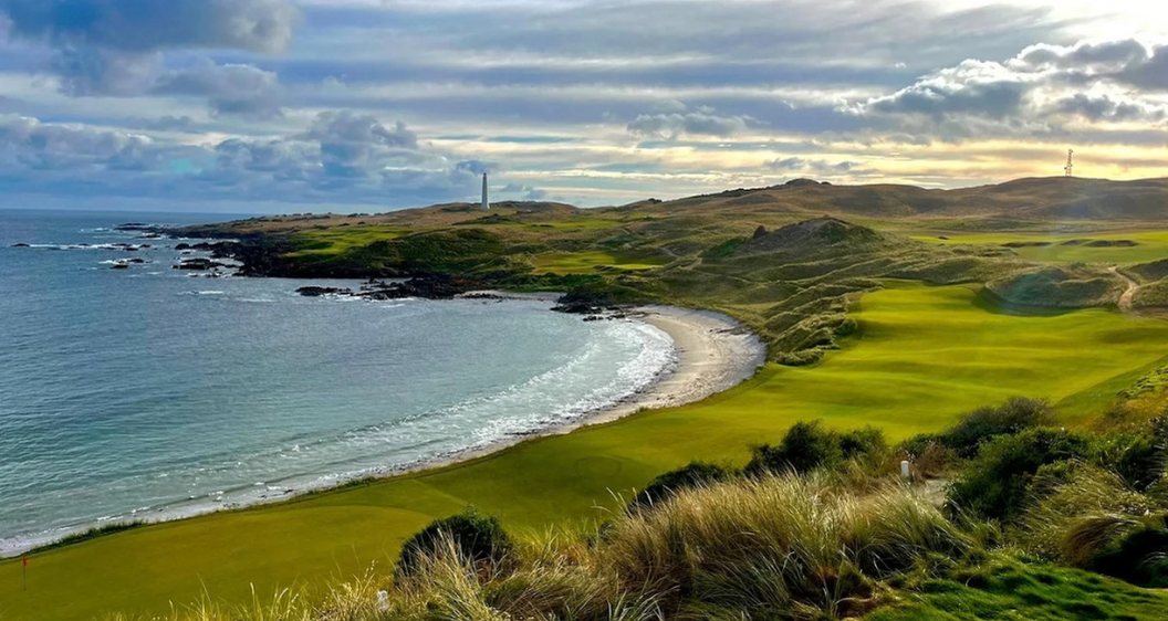 Illustrative coastal links golf scene with a white lighthouse, ocean surf, rocky headland and a green fairway for the Cape Wickham section.